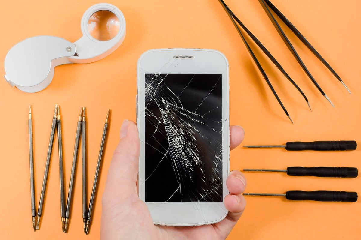 hand with smart phone with broken screen, Screwdrivers, tongs, magnifier. phone repair concept